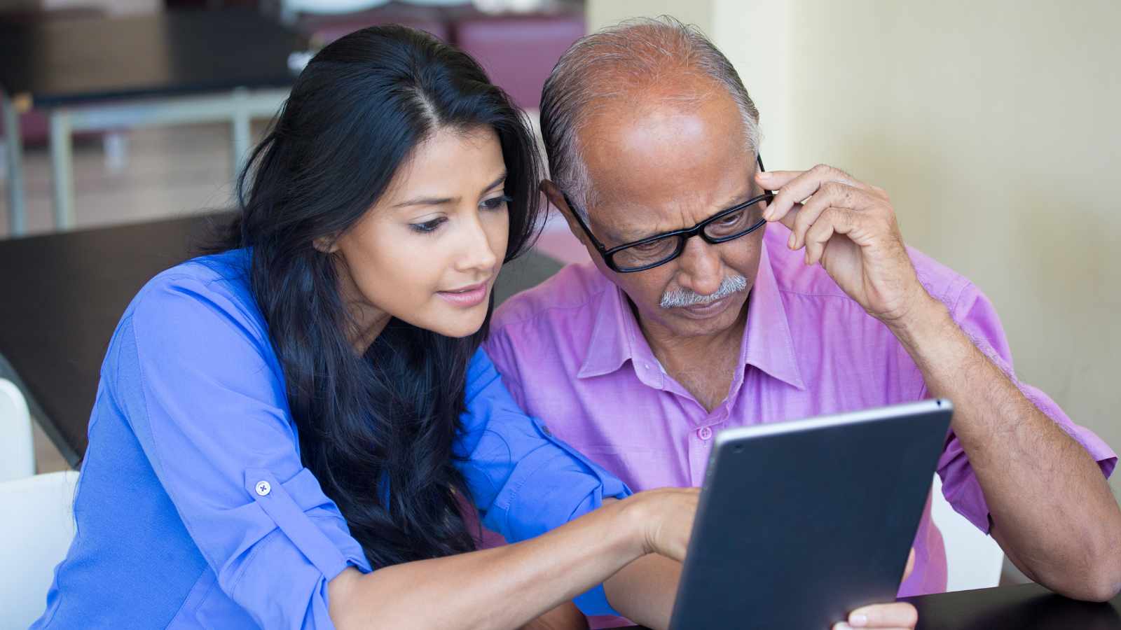 Lady showing an old man something on a ipad