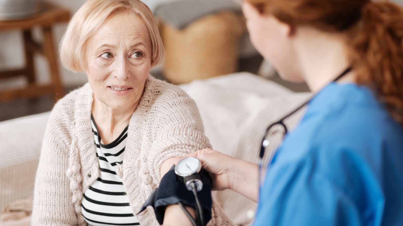 Nurse checking old ladys blood pressure