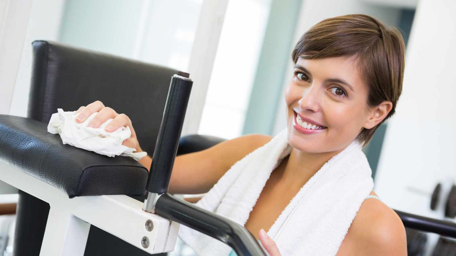 lady wiping down bench at the gym